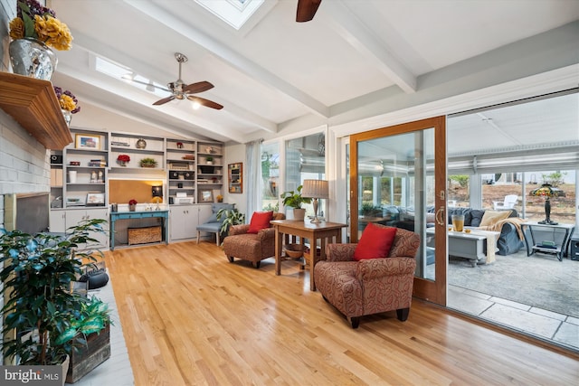 living area featuring vaulted ceiling with skylight, ceiling fan, and wood finished floors