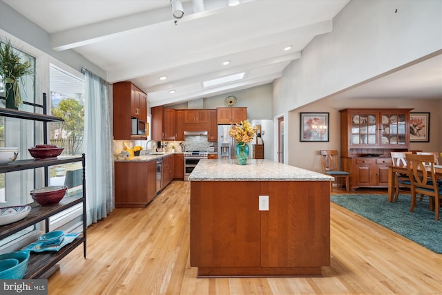 kitchen featuring brown cabinets, stainless steel appliances, lofted ceiling with beams, decorative backsplash, and a kitchen island