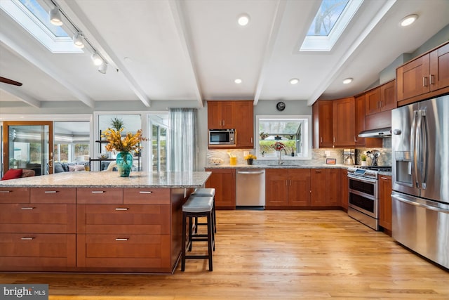 kitchen featuring stainless steel appliances, a breakfast bar, a sink, and tasteful backsplash