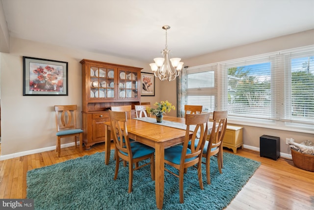 dining area featuring light wood-style floors, baseboards, and an inviting chandelier