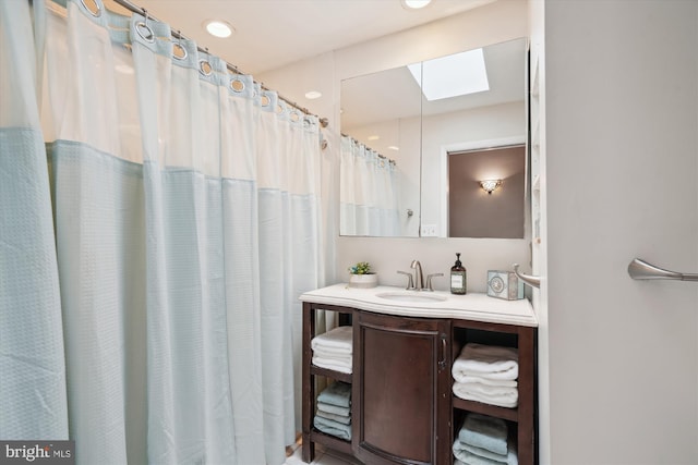 bathroom with curtained shower, a skylight, and vanity