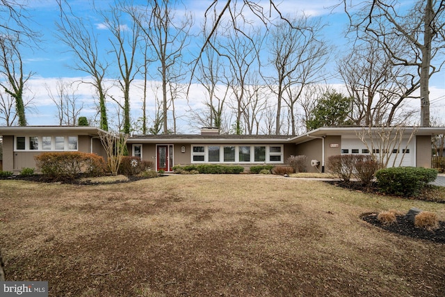 view of front of property with an attached garage, a chimney, and a front lawn