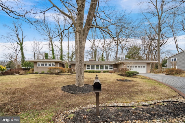 mid-century inspired home with an attached garage, driveway, fence, and a front lawn