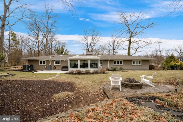 back of house featuring an outdoor fire pit, central air condition unit, a sunroom, a yard, and a patio area