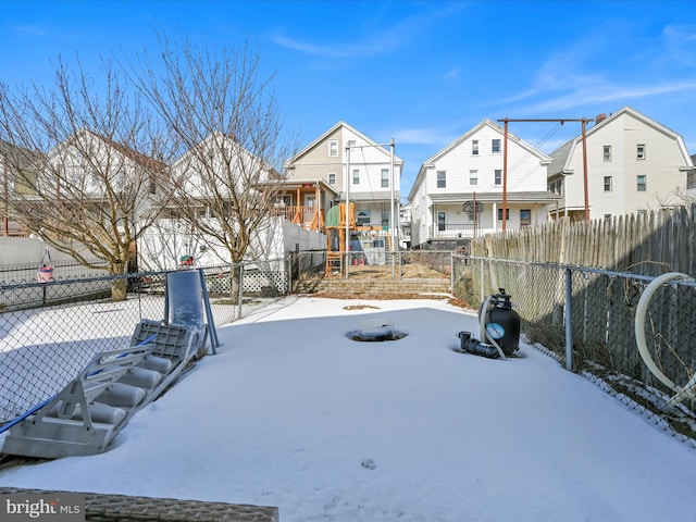 yard covered in snow with a residential view and fence