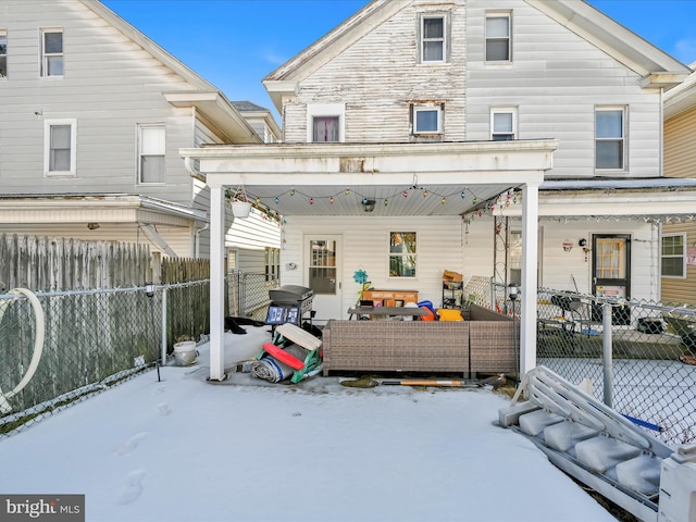 snow covered property featuring fence private yard, covered porch, and outdoor lounge area