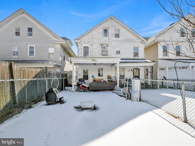 snow covered house featuring a porch and fence private yard