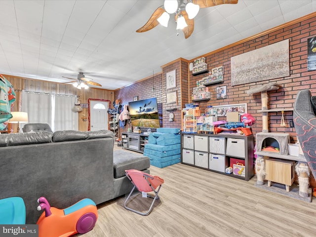 living area featuring light wood-style floors, ceiling fan, and brick wall