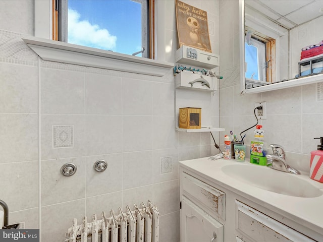 bathroom with tile walls, decorative backsplash, vanity, and radiator