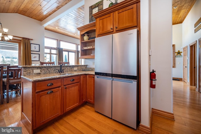 kitchen featuring a peninsula, open shelves, a sink, and freestanding refrigerator