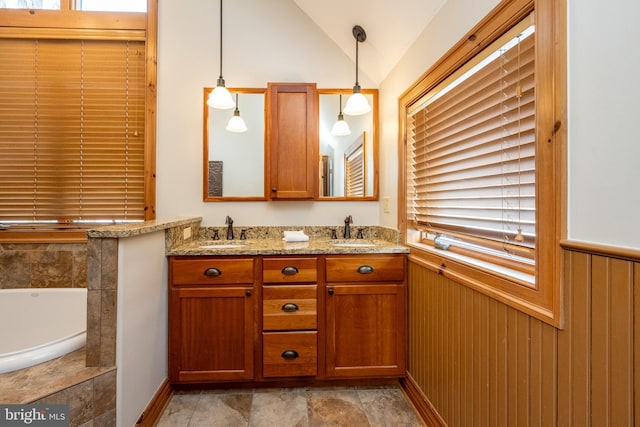 bathroom with double vanity, vaulted ceiling, a sink, and wainscoting