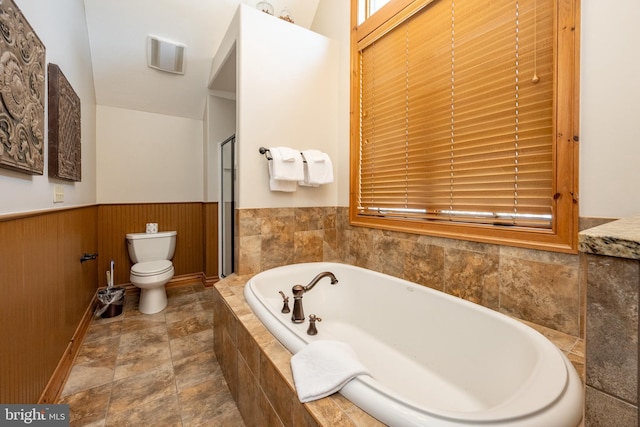 bathroom with wainscoting, a garden tub, and toilet