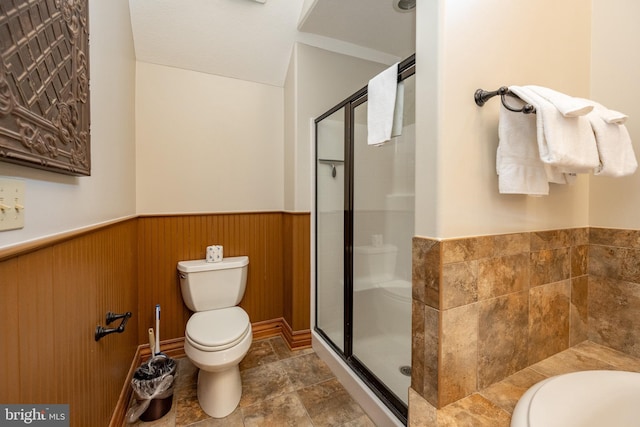 full bathroom with toilet, a wainscoted wall, a shower stall, and wood walls