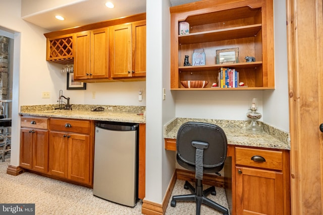 kitchen featuring recessed lighting, built in study area, freestanding refrigerator, light stone countertops, and open shelves