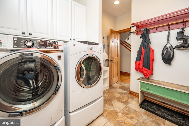 laundry room featuring recessed lighting, cabinet space, washing machine and dryer, stone finish flooring, and baseboards