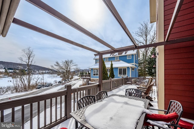 snow covered deck with outdoor dining area and a pergola