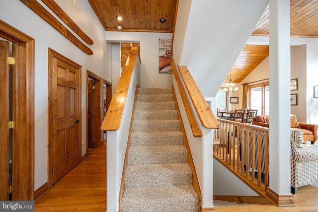 stairs featuring wooden ceiling, vaulted ceiling, an inviting chandelier, and wood finished floors