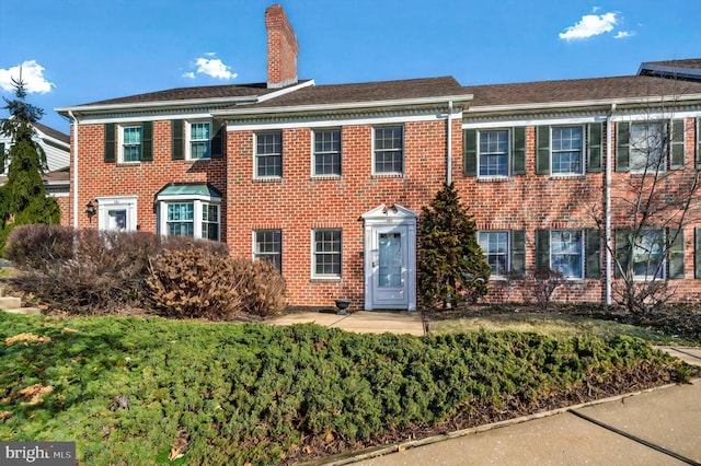 view of front of house with brick siding and a chimney