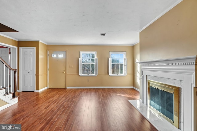 interior space with wood finished floors, a high end fireplace, baseboards, ornamental molding, and stairway