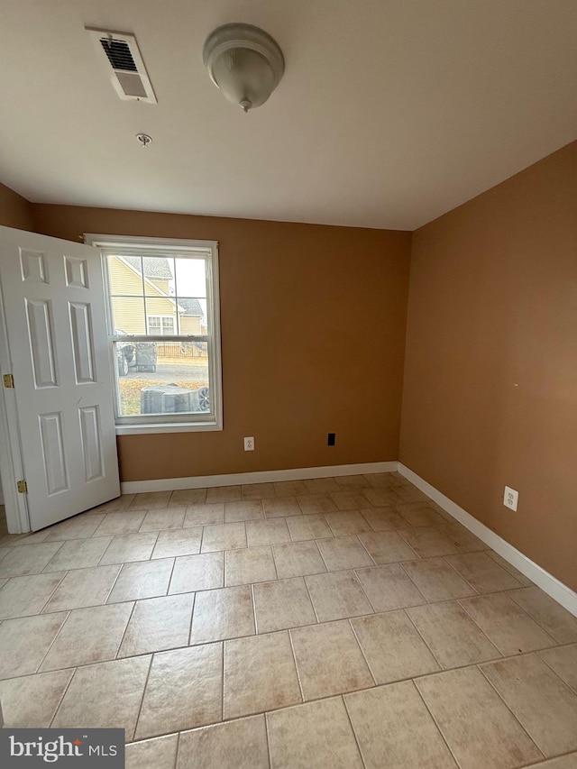 empty room featuring light tile patterned floors, visible vents, and baseboards