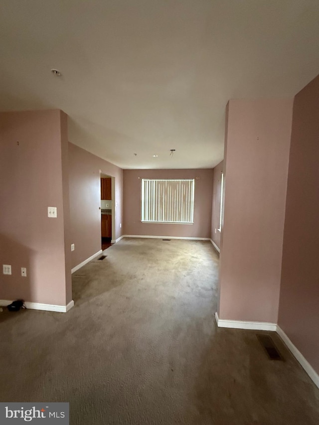 carpeted spare room featuring visible vents and baseboards