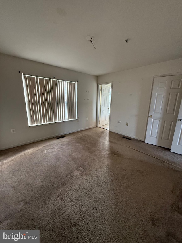 spare room with visible vents, baseboards, and carpet flooring