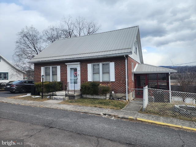 bungalow-style home featuring brick siding, metal roof, and fence