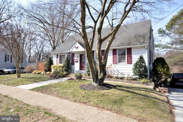 view of front facade with a front lawn and a shingled roof