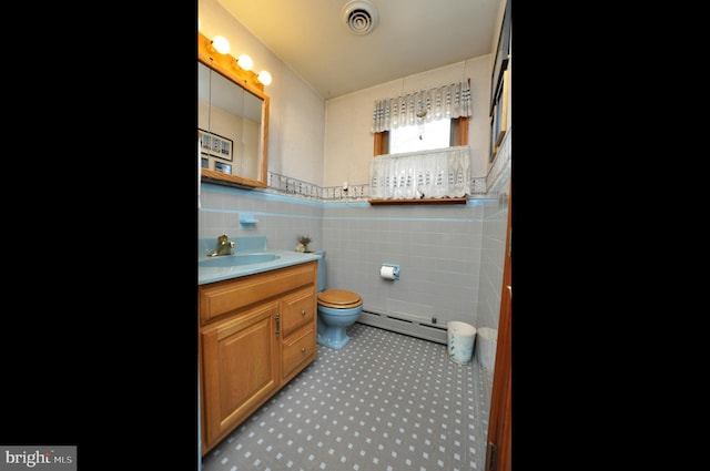 bathroom featuring visible vents, tile walls, toilet, vanity, and a baseboard radiator