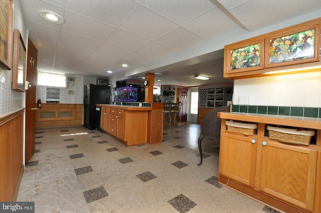 kitchen with a drop ceiling, plenty of natural light, tile counters, and freestanding refrigerator