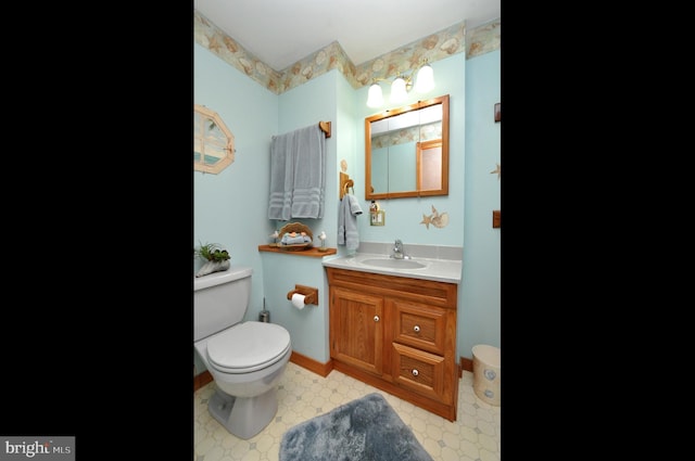 bathroom featuring toilet, vanity, and baseboards