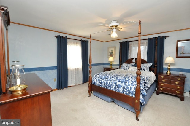 bedroom with crown molding, carpet flooring, a ceiling fan, and wainscoting