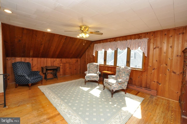 living area with baseboard heating, wooden walls, and hardwood / wood-style flooring