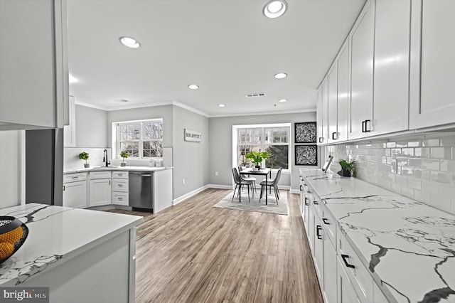 kitchen with ornamental molding, light wood-style floors, white cabinetry, and dishwasher