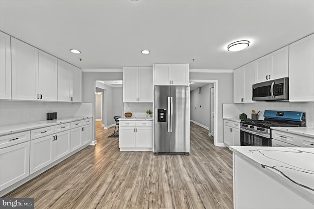 kitchen with appliances with stainless steel finishes, white cabinetry, and crown molding