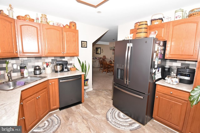 kitchen featuring tasteful backsplash, light countertops, a sink, stainless steel fridge, and dishwasher