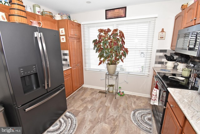 kitchen featuring light wood-type flooring, stainless steel refrigerator with ice dispenser, decorative backsplash, brown cabinets, and black electric range oven