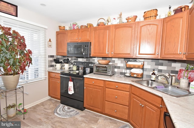 kitchen featuring black range with electric cooktop, a toaster, a sink, light countertops, and tasteful backsplash