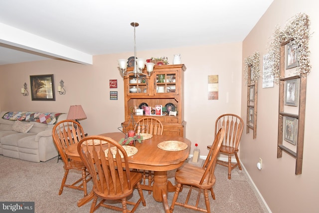 dining space featuring light carpet, baseboards, a notable chandelier, and beamed ceiling