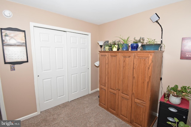 carpeted bedroom featuring baseboards and a closet