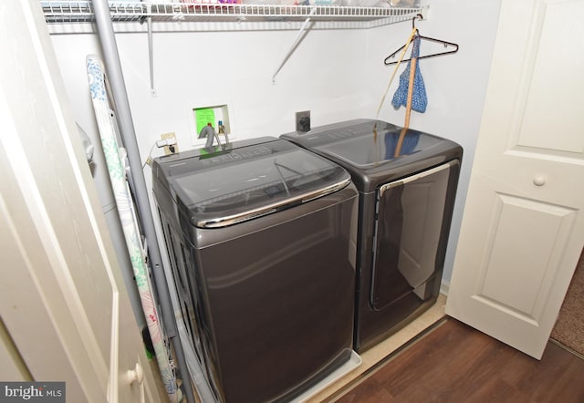 clothes washing area featuring dark wood-style floors, washer and dryer, and laundry area