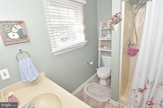 bathroom with toilet, a shower stall, and baseboards