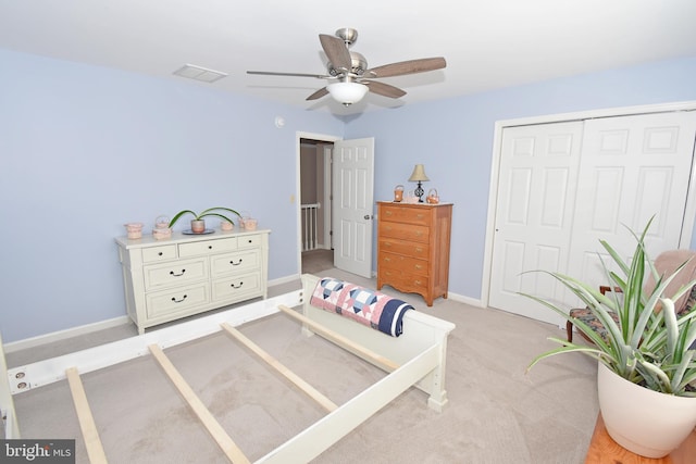 bedroom with a closet, visible vents, light carpet, ceiling fan, and baseboards