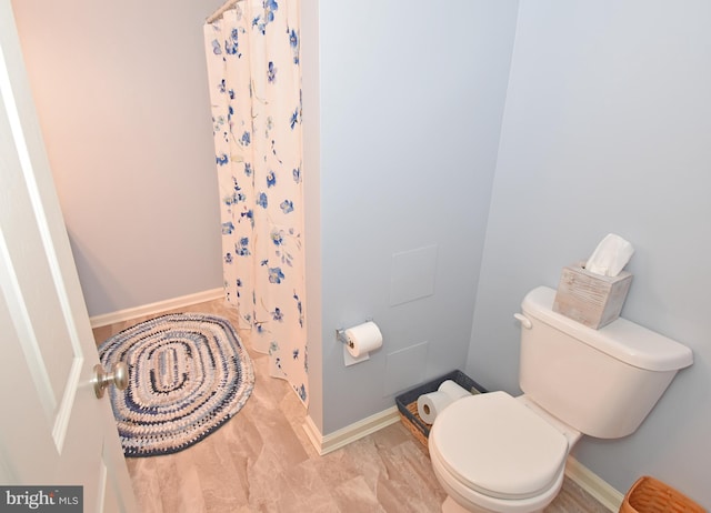 bathroom with toilet, a shower with curtain, and baseboards