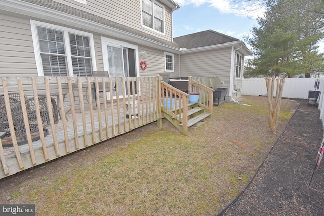 exterior space with a yard, fence, a deck, and roof with shingles