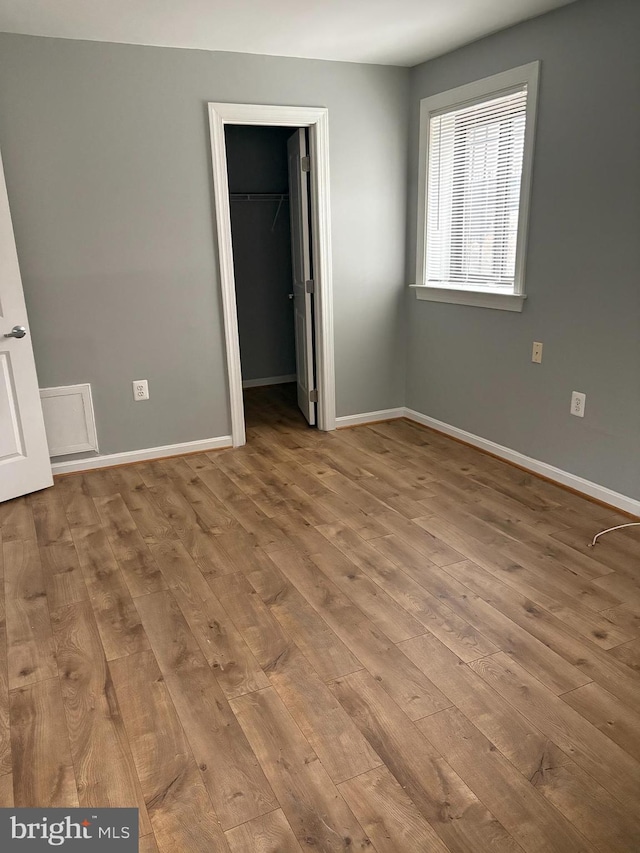 unfurnished bedroom featuring a spacious closet, light hardwood / wood-style floors, and a closet