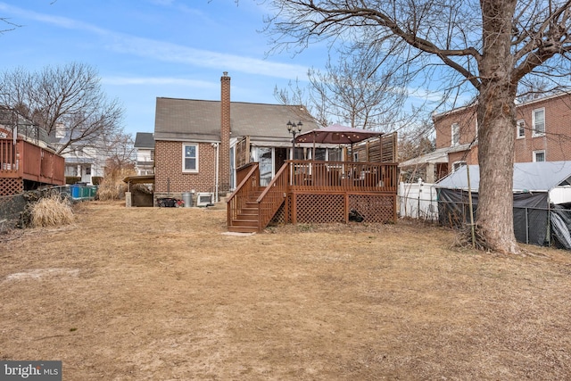 rear view of house with brick siding, a gazebo, stairway, a wooden deck, and a chimney