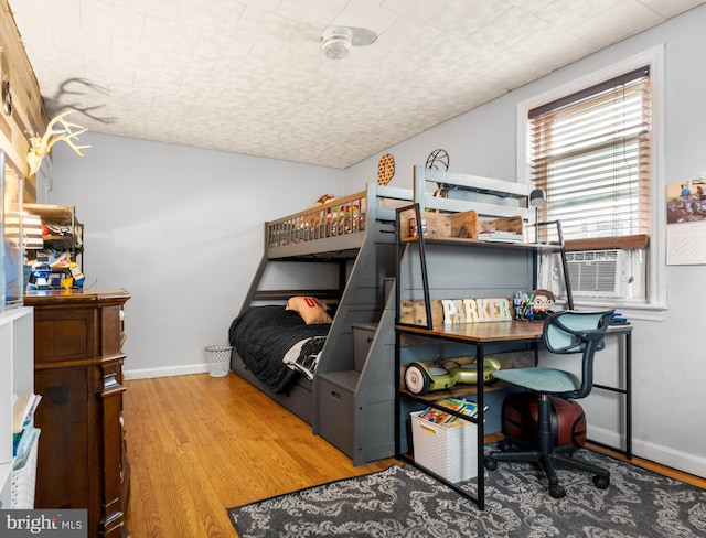 bedroom with lofted ceiling, cooling unit, wood finished floors, and baseboards