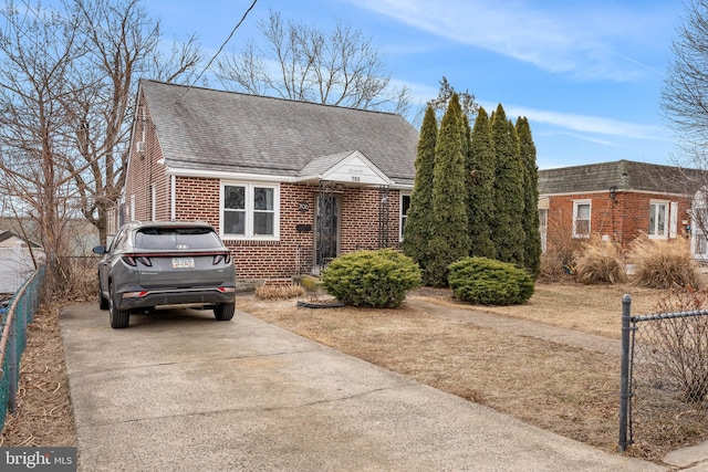 view of front of home with roof with shingles, fence, and brick siding