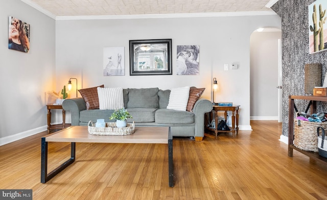 living room with baseboards, crown molding, arched walkways, and wood finished floors